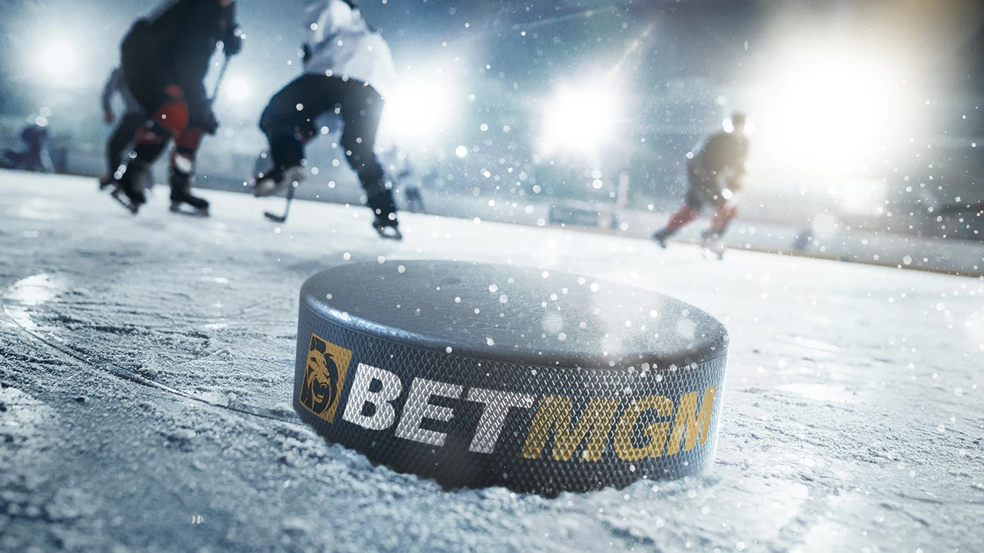 Tre ishockeyspelare spelar ishockey mot varandra och på isen ligger det en puck med en logga på BetMGM